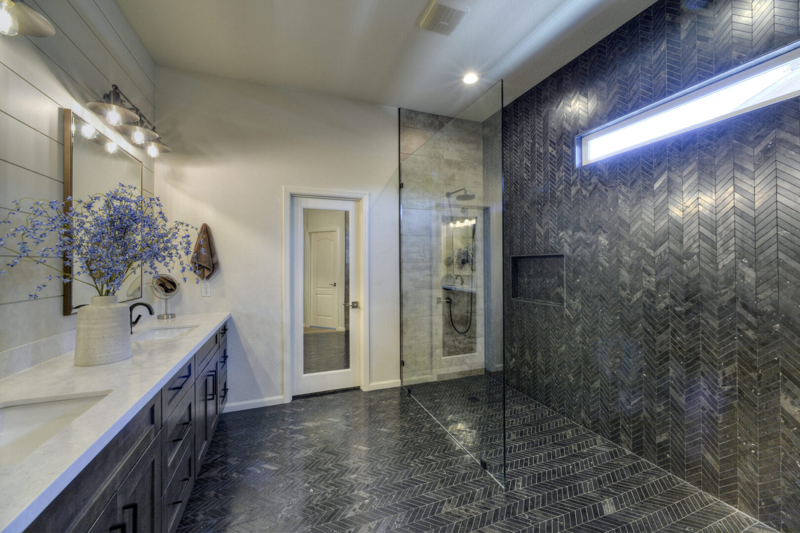 A bathroom with a walk in shower and double sinks.