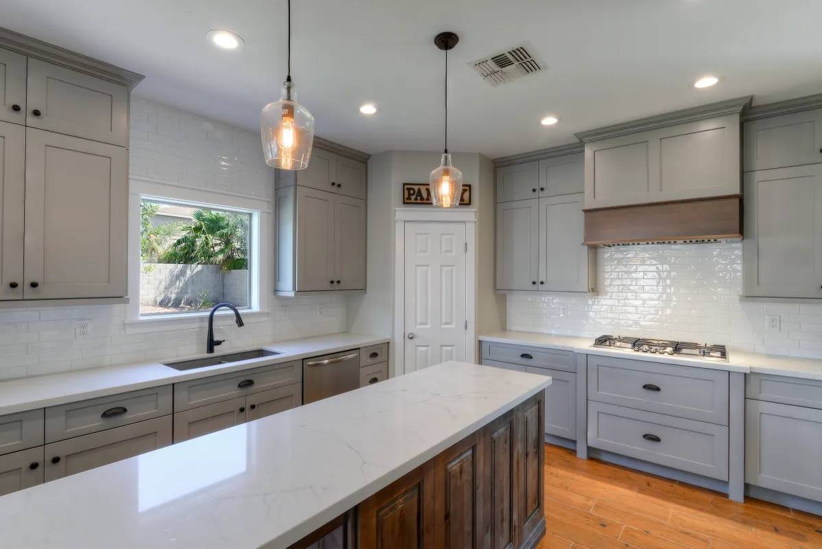 A kitchen with white cabinets and wooden floors.