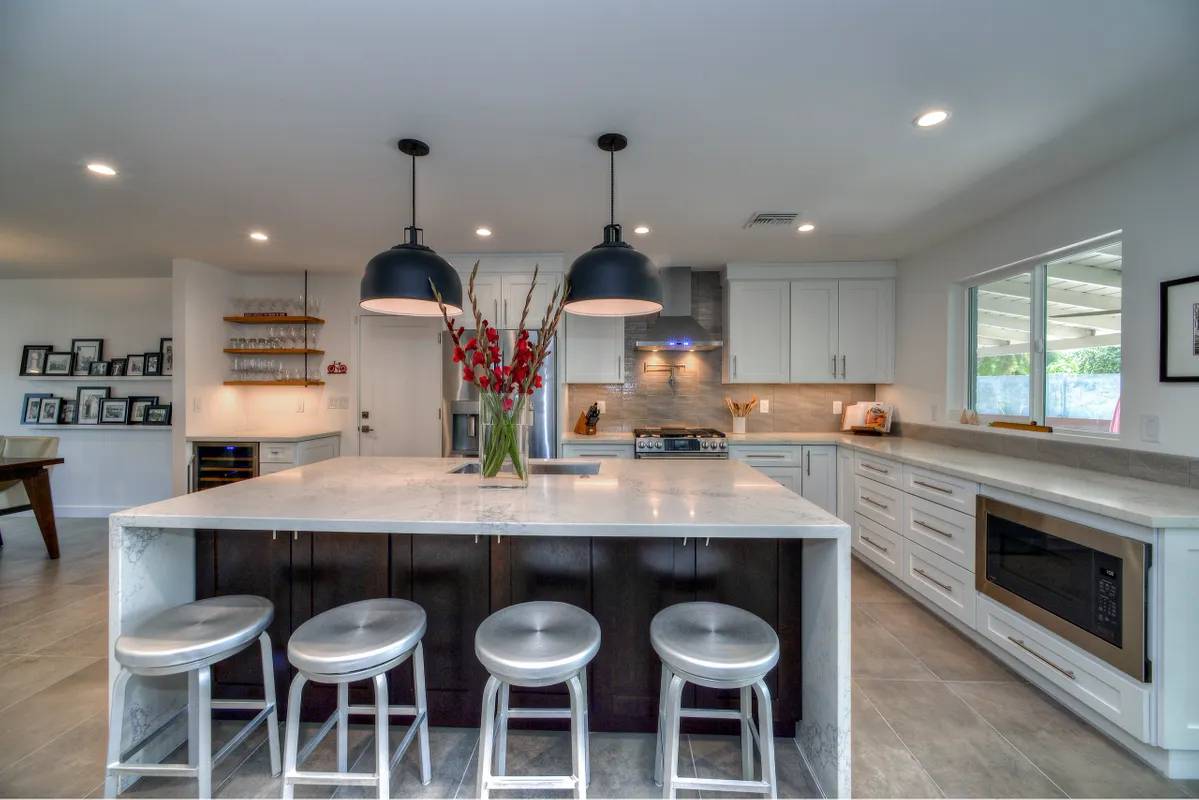 A large kitchen with white cabinets and black lights.