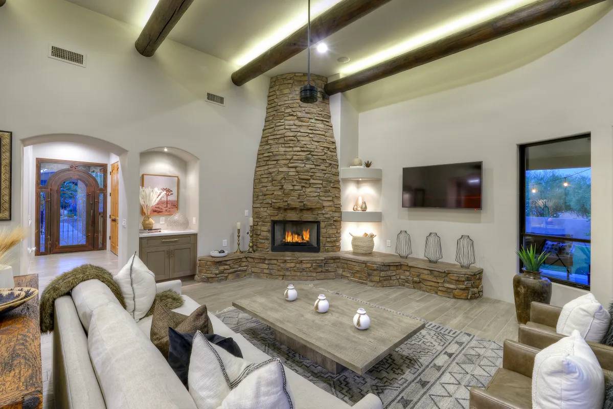 A living room with a fireplace and a large stone wall.