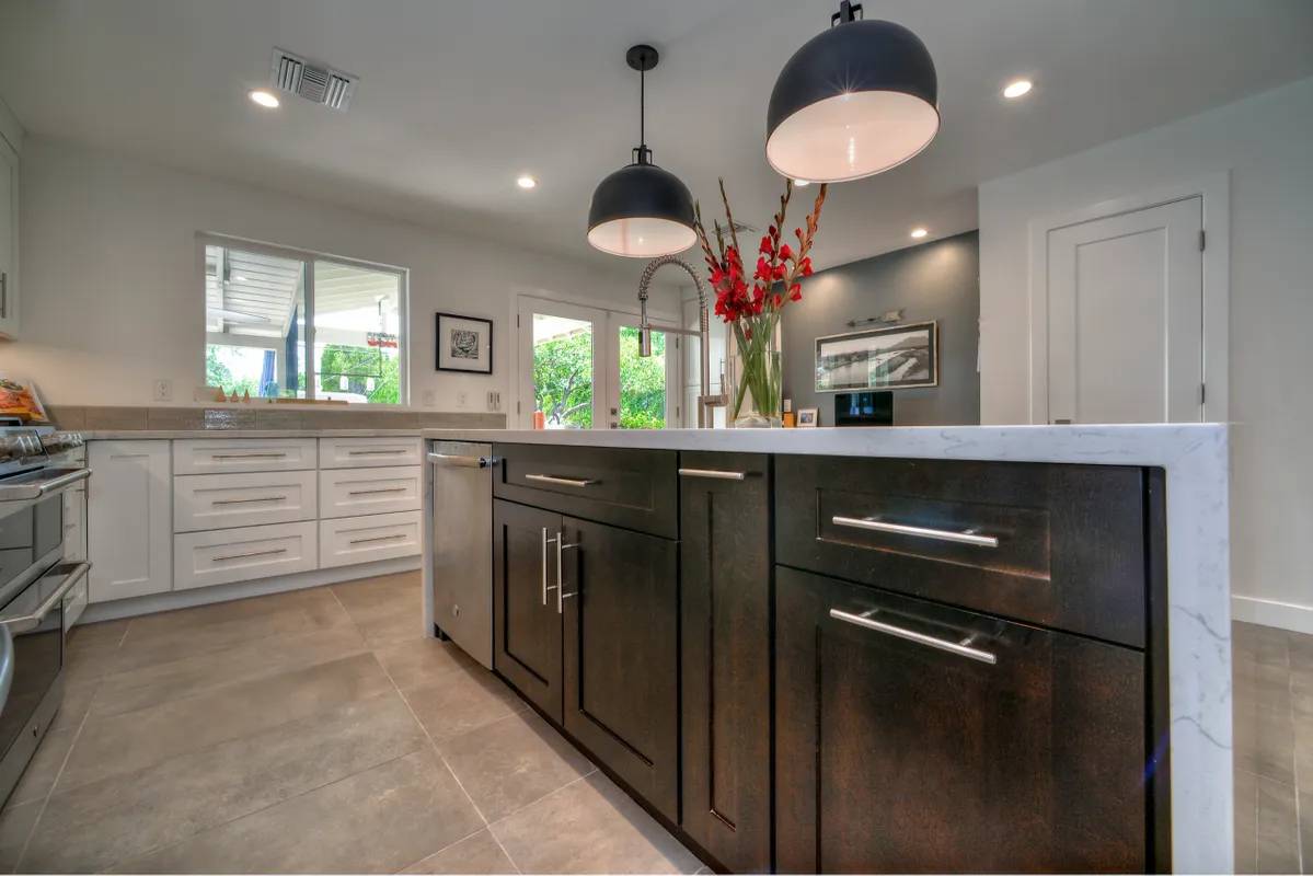 A kitchen with black cabinets and white counters.