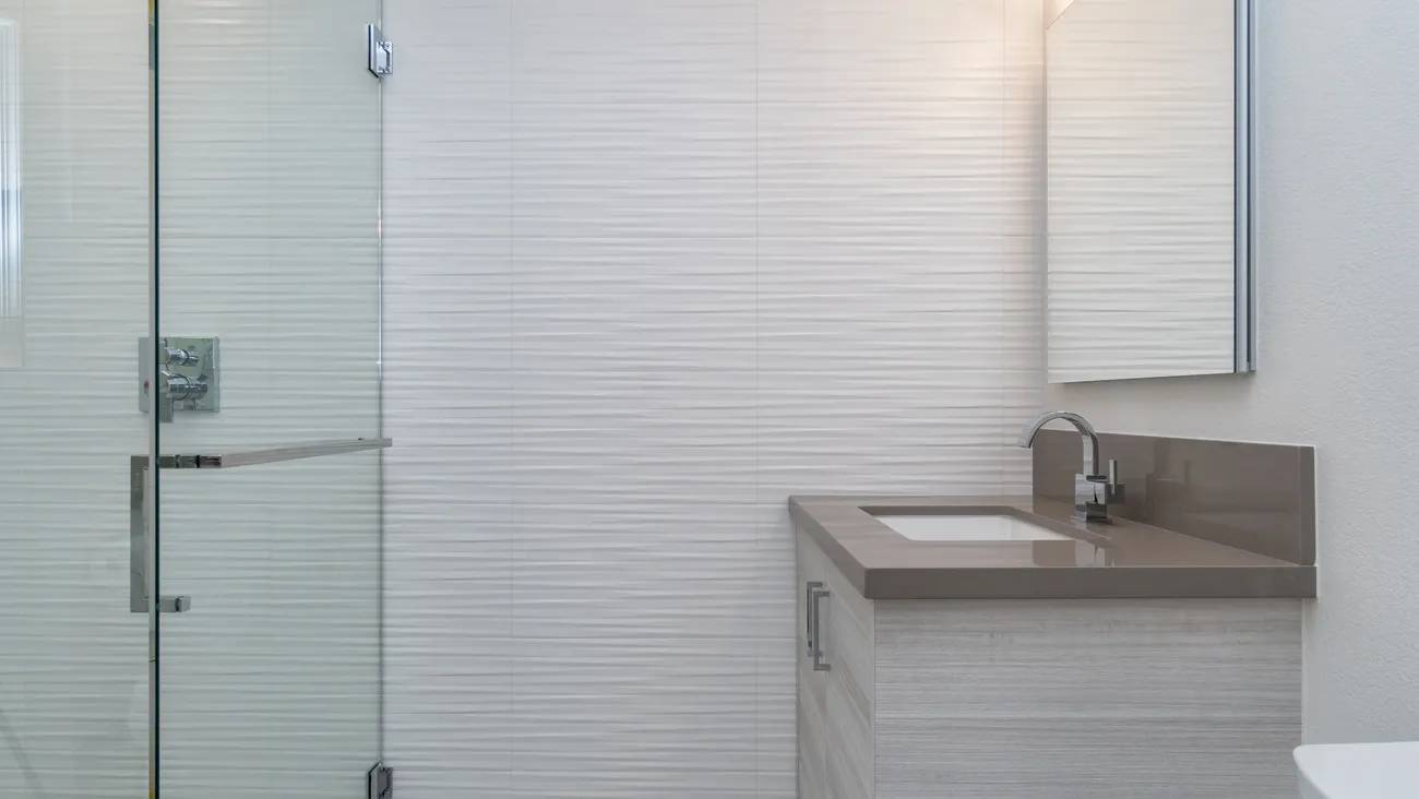 A bathroom with white tile and a sink.