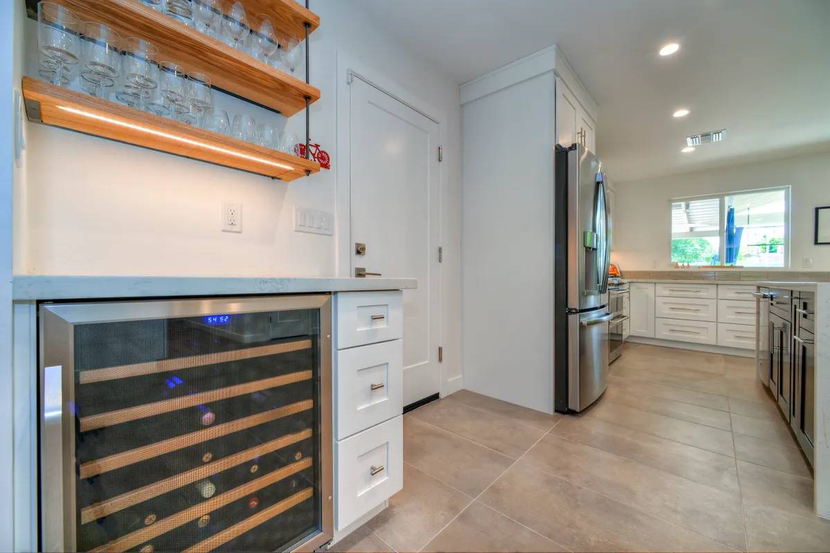 A kitchen with white cabinets and wood floors.