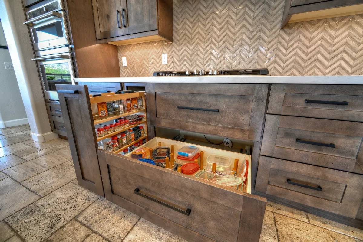 A kitchen with wooden cabinets and drawers filled with food.