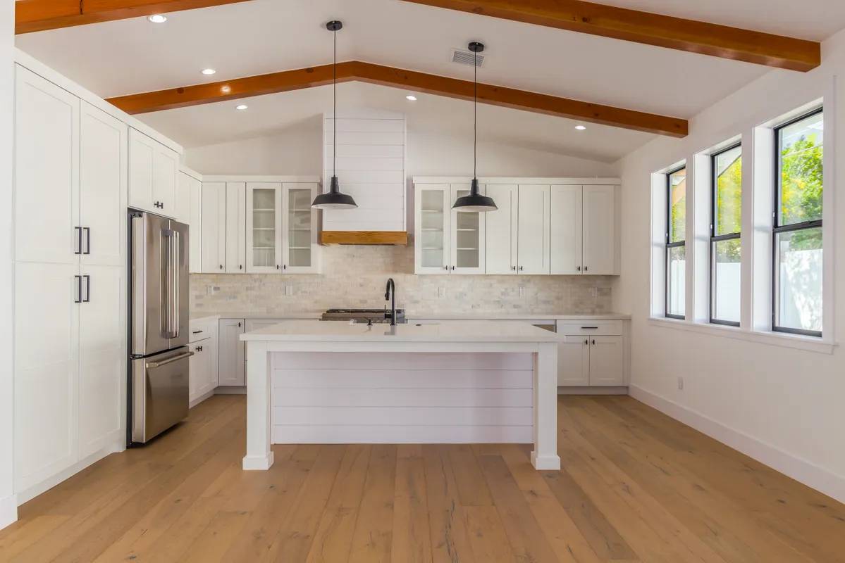 A kitchen with white cabinets and wooden floors.