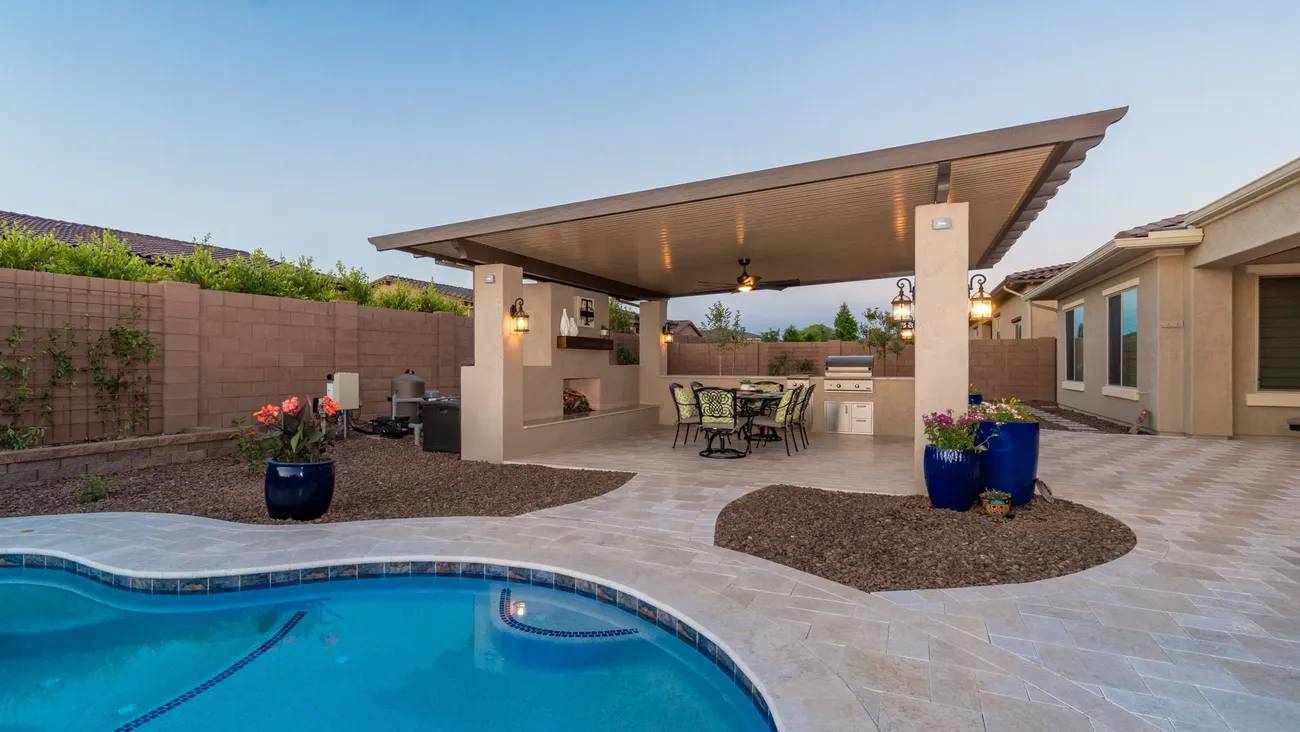A pool with an outdoor kitchen and dining area.