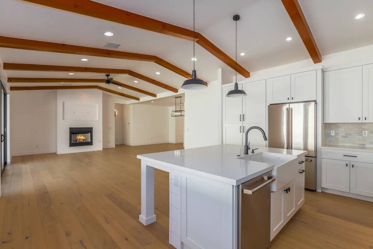 A kitchen with white cabinets and wood floors.