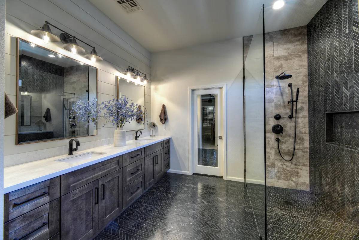 A bathroom with two sinks and a walk in shower.