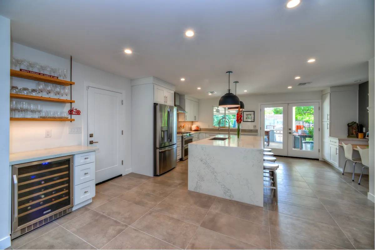 A kitchen with marble counter tops and white cabinets.