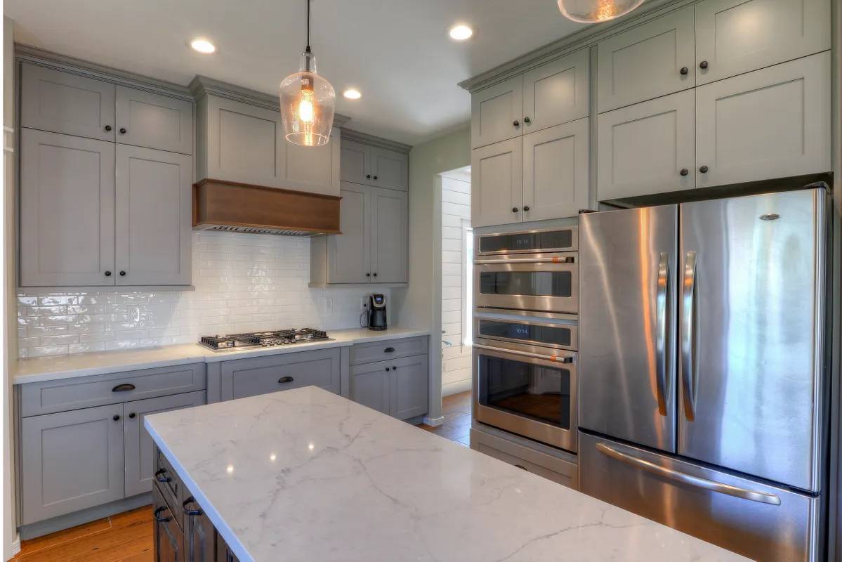 A kitchen with grey cabinets and stainless steel appliances.