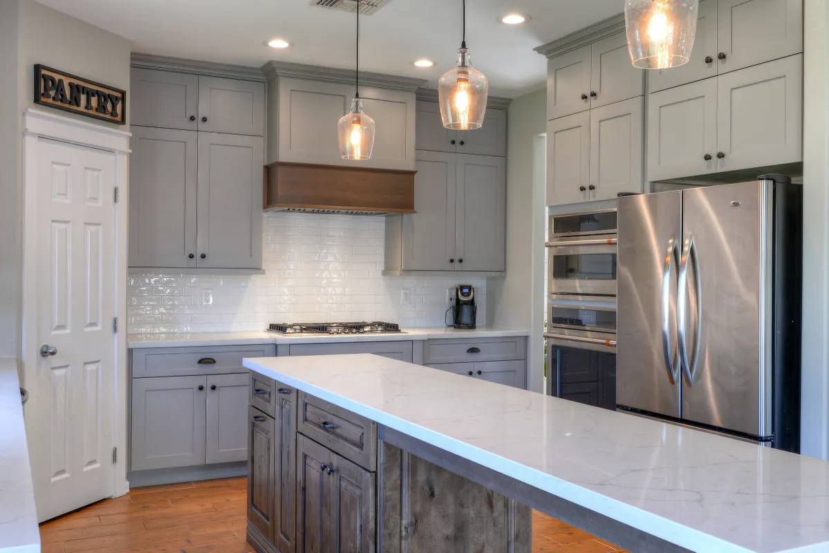 A kitchen with grey cabinets and stainless steel appliances.