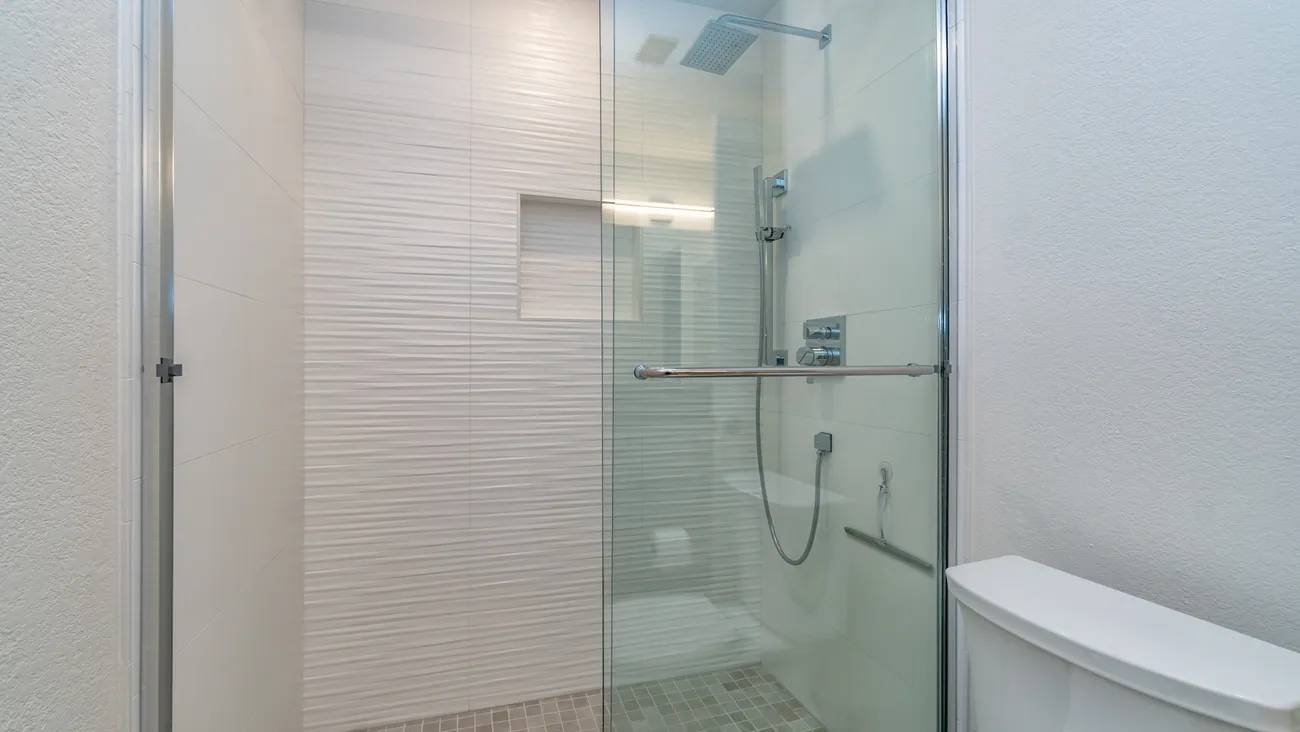 A bathroom with a walk in shower and tiled walls.
