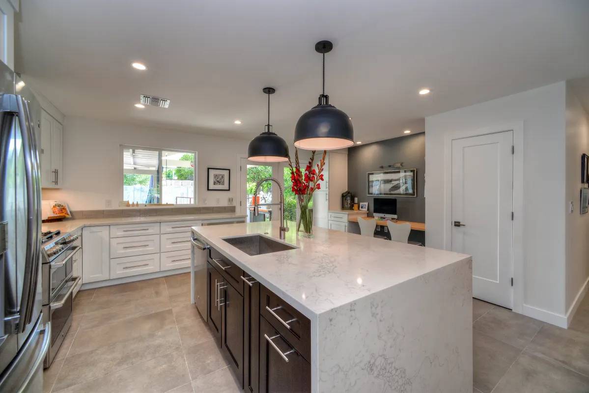 A kitchen with white counters and black lights