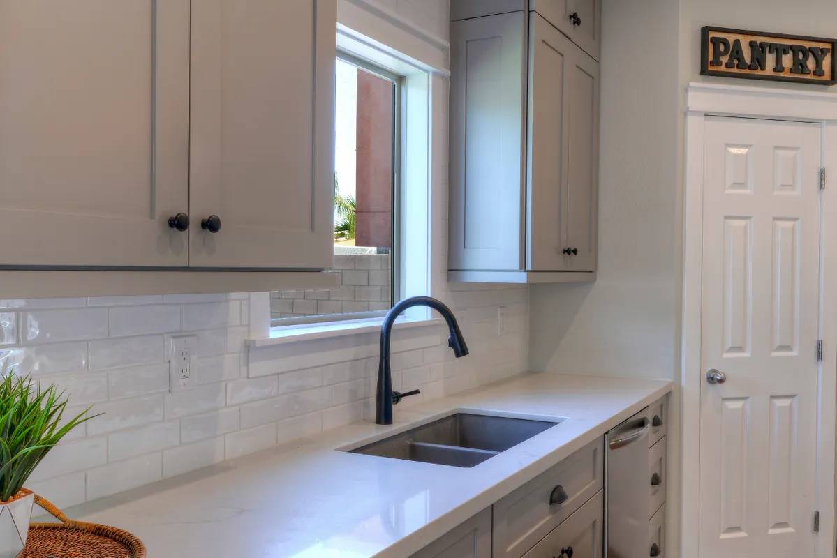 A kitchen with white cabinets and black faucet.